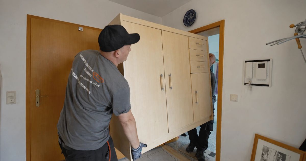 Zwei Mitarbeiter des Entrümpelungstrupps Scherzer tragen einen Schrank aus einer Wohnung in Nürnberg
